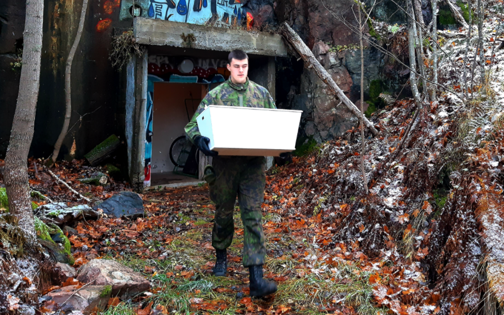 Kaartinjääkäri Toni Leppäaho kantaa kotiutettavaa arkkua luolasta autoon (Kuva Pertti Suominen)